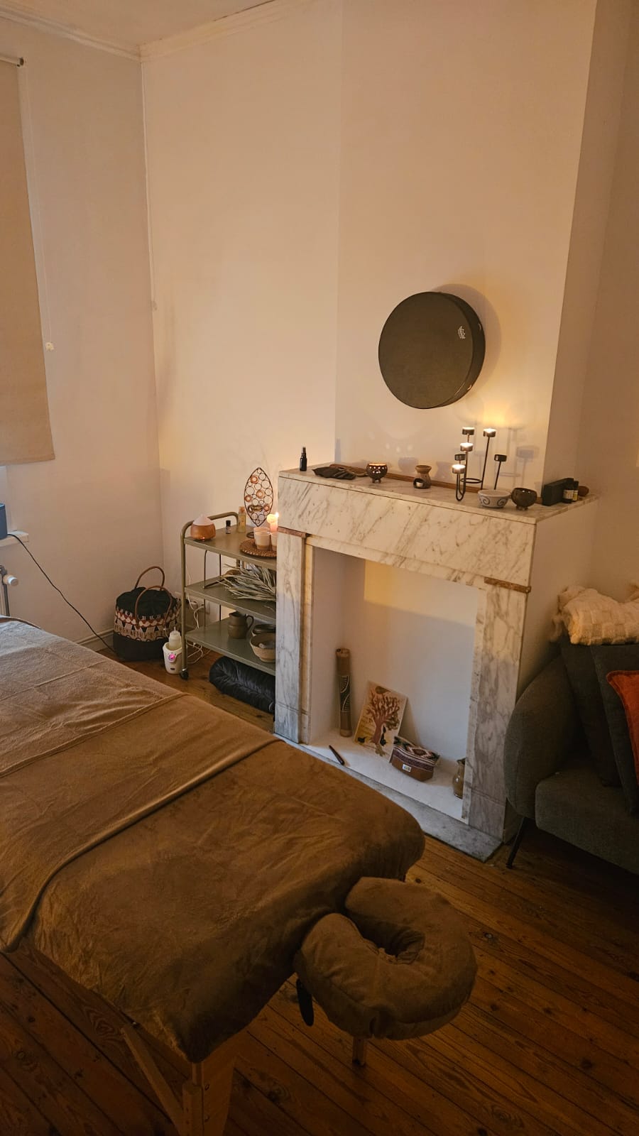 De warme praktijkruimte met massagetafel en schouw